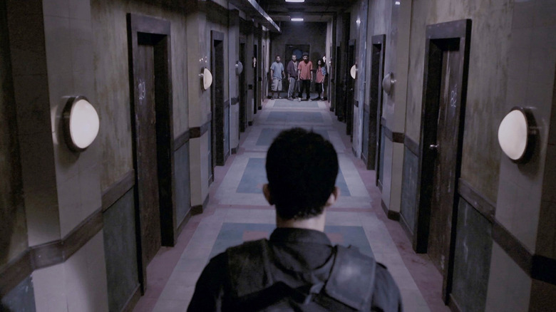 Iko Uwais as Rama, facing down thugs at end of hallway in The Raid Redemption