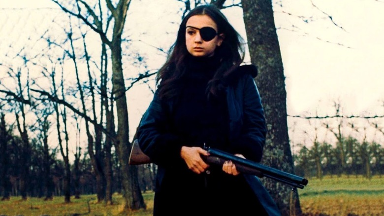 Madeleine holds a shotgun