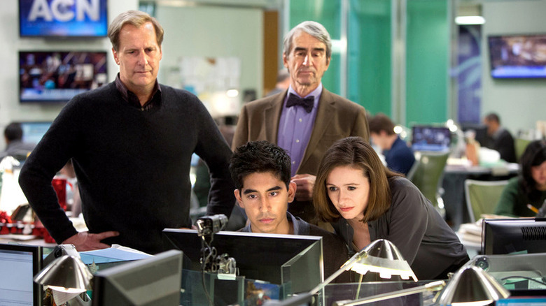 Employees gathered around a desk on "The Newsroom"