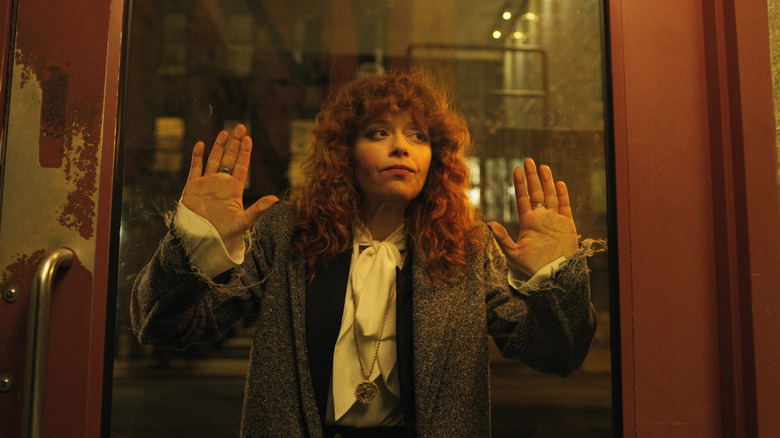 Natasha Lyonne as Nadia Vulvokov holding her hands up a glass panel in a door in Russian Doll