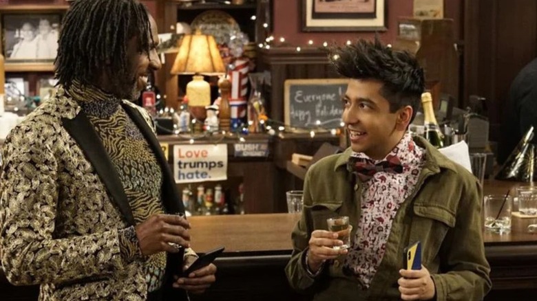 Nik Dodani as Pat Patel, talking to someone at a bar on Murphy Brown
