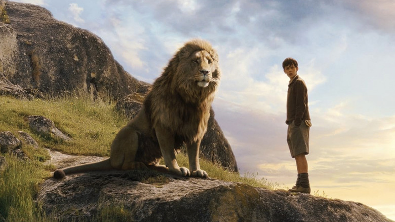 Aslan standing next to young Edmund on a rocky surface in The Lion The Witch and the Wardrobe