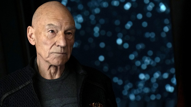 Patrick Stewart as Jean-Luc Picard standing by a window displaying a field of stars in Star Trek: Picard
