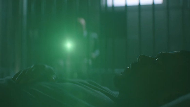 Nathan Fillion's Guy Gardner sits shining the light from his ring on Aaron Pierre's John Stewart in a jail in Lanterns