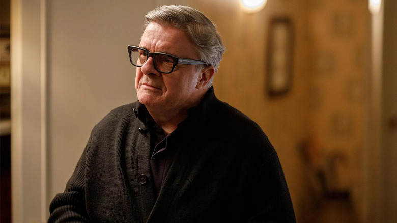 nathan lane as teddy dimas wearing a black sweater and glasses on the tv show only murders in the building
