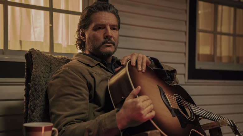 Joel holding his guitar on the porch on The Last of Us