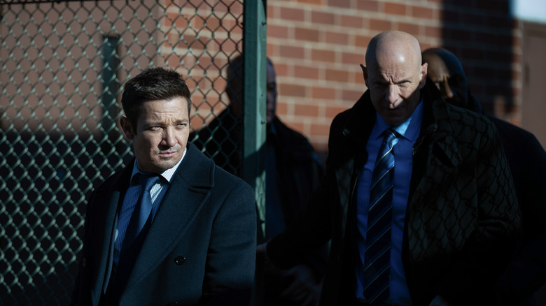 Jeremy Renner's Mike McLusky and Hugh Dillon's Ian Ferguson walk through a gate in Mayor of Kingstown