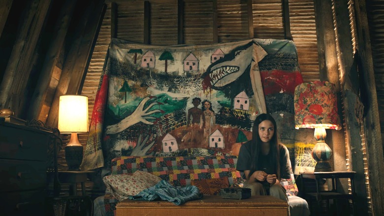Hannah Cheramy's Julie Matthews sits in front of a tapestry showing a town being menaced by creatures in From