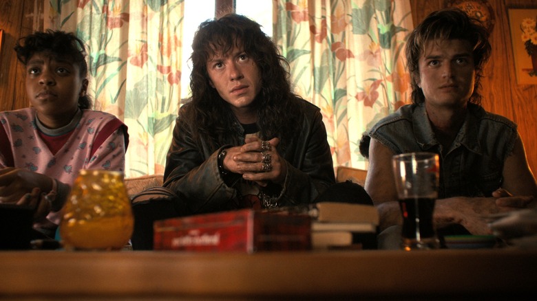 Erica, Eddie, and Steve sitting on a couch in Stranger Things season 4