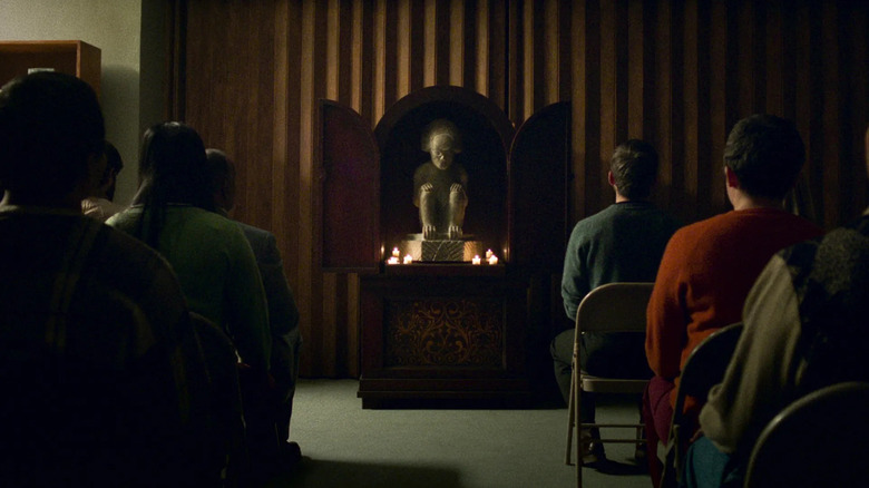Cult members sitting down and looking at a statue on "Archive 81."