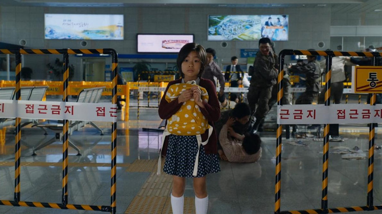 Kim Su-an as Su-an holds a backpack while zombies run towards her in Train to Busan