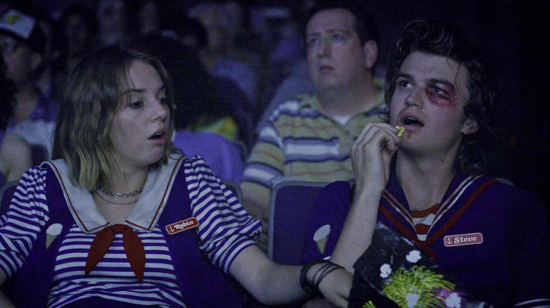 Robin and Steve eating popcorn in a theater in Stranger Things
