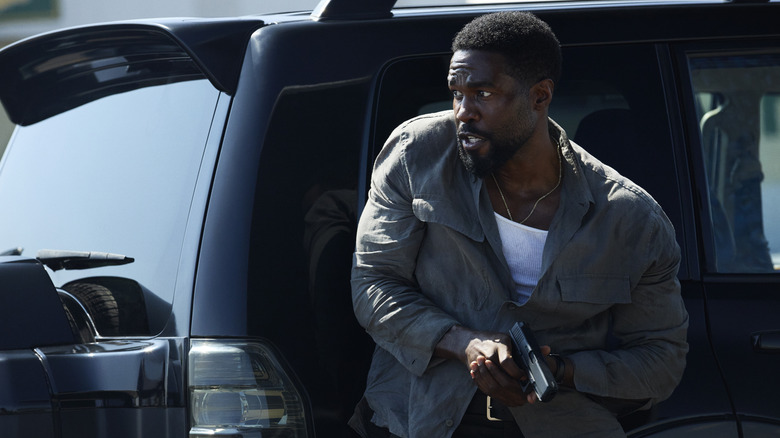 Yahya Abdul-Mateen ll as John Creasy holding a gun standing by an SUV in Man on Fire (2026)