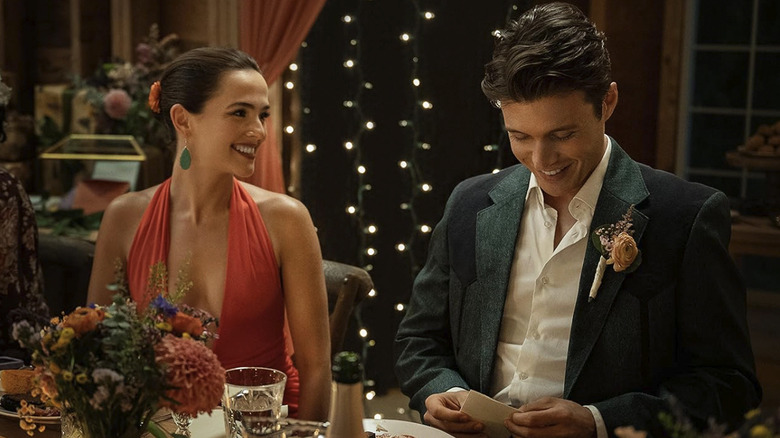 A nicely dressed Jill smiles at a suit-wearing Wes while he looks down at a note in his hand in Voicemails for Isabelle