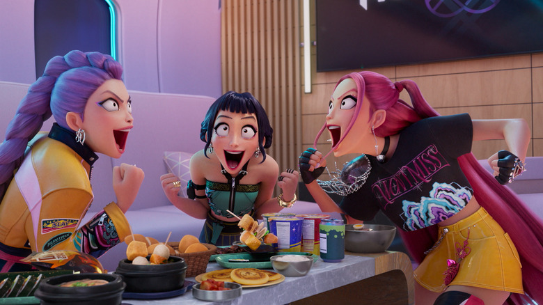 The members of HUNTR/X smiling and celebrating while eating a feast in KPop Demon Hunters