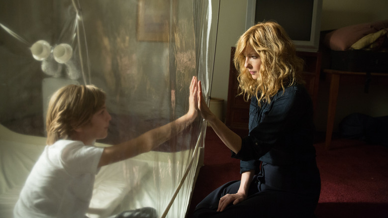 Max Martini as Eli touching hands through plastic with Kelly Reilly as Rose in Eli