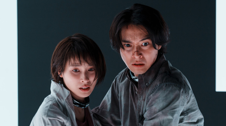 Tao Tsuchiya as Yuzuha Usagi and Kento Yamazaki as Ryohei Arisu wearing collars and looking concerned in Alice in Borderland season 3