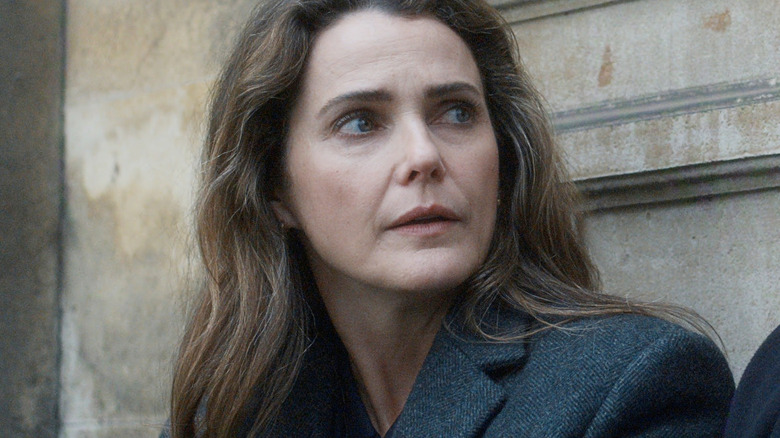Keri Russell as Kate Wyler sitting against a granite pillar in The Diplomat