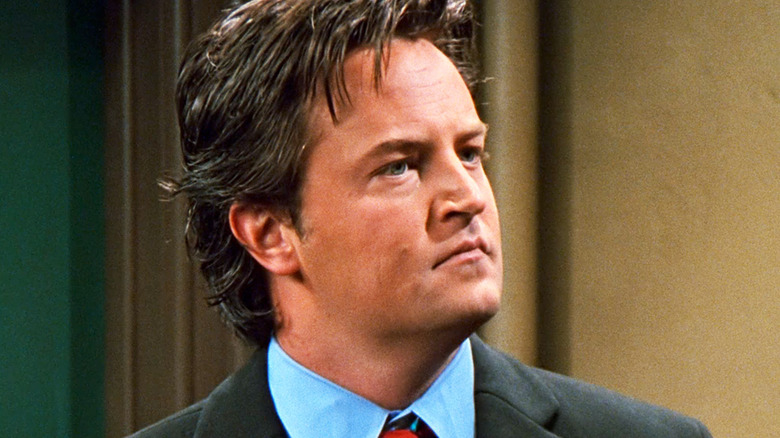 Matthew Perry's Chandler Bing stands in an apartment hallway in Friends