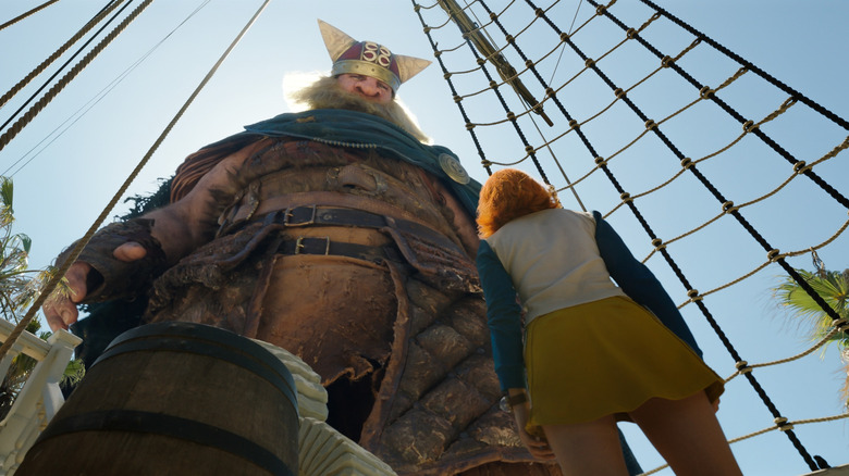 Brogy the giant looks at tiny Nami with curiosity in One Piece