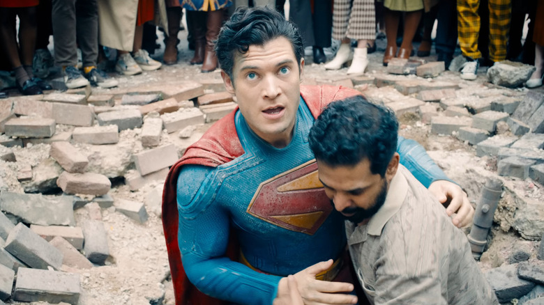 Superman cradling someone and standing in rubble in "Superman"