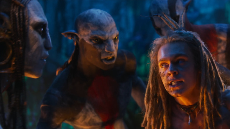 Sam Champion as Spider being held hostage by Oona Chaplin as Varang in the middle of a jungle in Avatar: Fire and Ash