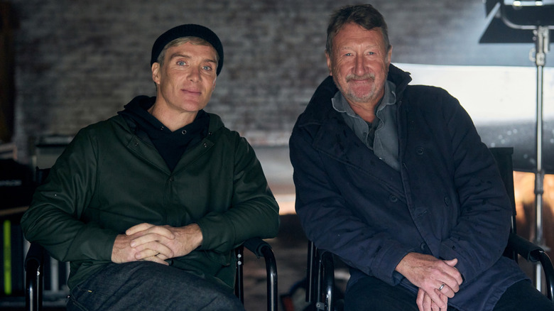 Cillian Murphy as Thomas Shelby sitting next to creator Steven Knight in a behind-the-scenes picture for Peaky Blinders