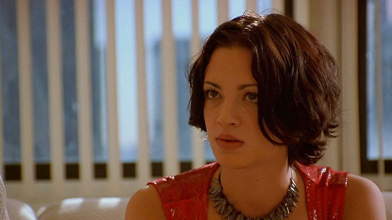 Sandii wearing a sleeveless red top in New Rose Hotel