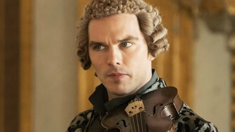 Nicholas Hoult as Peter, with a violin to his neck and looking off camera, in The Great