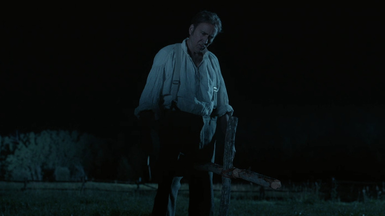 Nicolas Cage's Colton Briggs stands next to a makeshift grave at night in The Old Way
