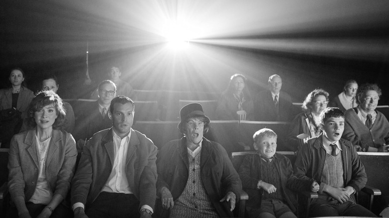 several movie theatre goers watching with a projection light behind them