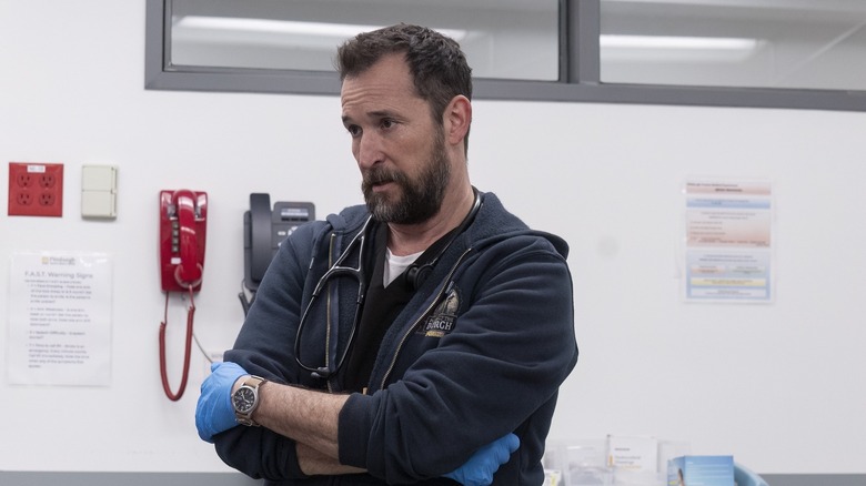 Dr. Robby crossing his arms in scrubs and a hoodie on The Pitt