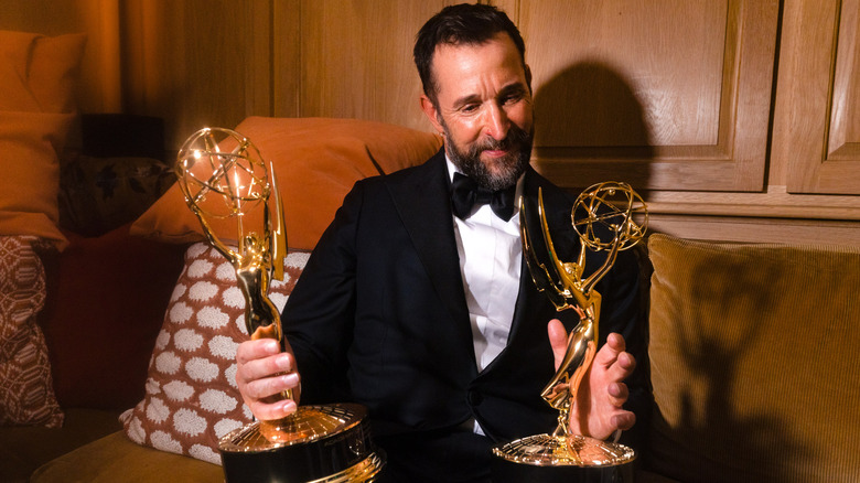 Noah Wyle gazing at his two Emmy Awards