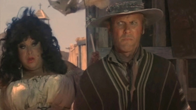 Divine as Rosie Velez and Tab Hunter as Abel Wood standing side-by-side in a western town in Lust in the Dust