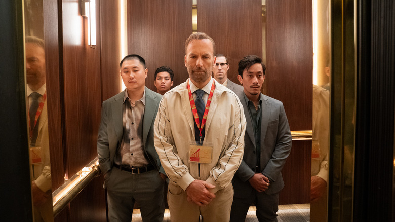 Hutch Mansell in an elevator surrounded by suspicious looking fellows in Nobody 2