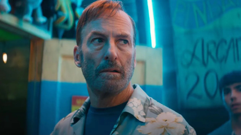 Hutch looks serious surrounded by people and neon in Nobody 2