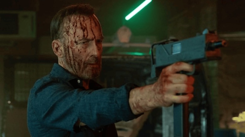Bod Odenkirk como Hutch sosteniendo una ametralladora ensangrentada en nadie 2