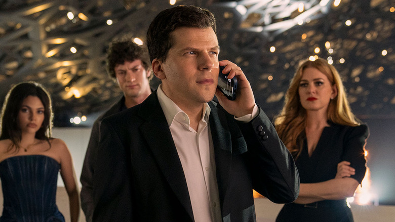 Jesse Eisenberg as J. Daniel Atlas talking on the phone in front of the other Horsemen in Now You See Me: Now You Don't