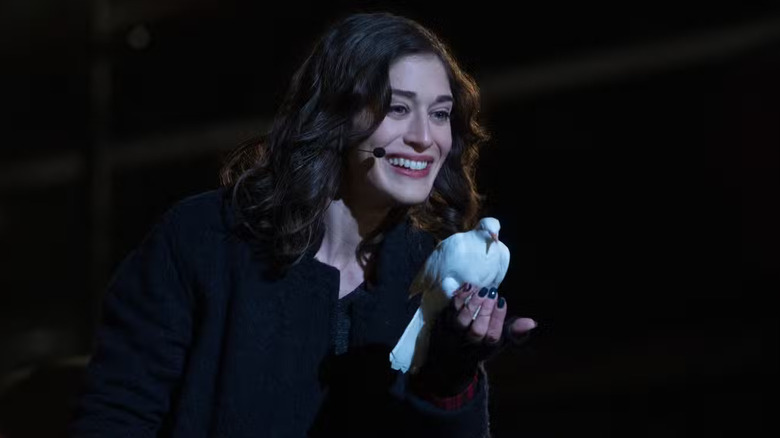 Lula smiling onstage wearing a microphone and holding a dove in Now You See Me 2