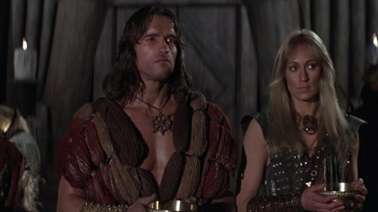 Conan in een vest naast een blonde vrouw in Conan the Barbarian