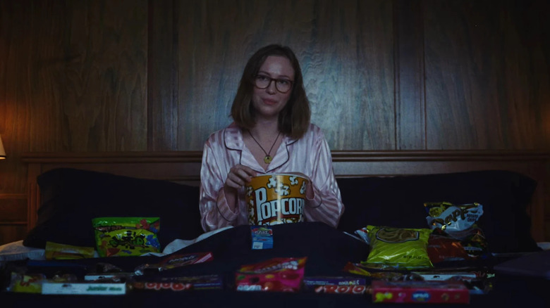 Kris watching slasher movies and eating movie snacks in Teenage Sex and Death at Camp Miasma