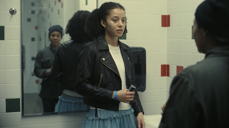 Chase Infiniti as Willa staring uncertainly at Regina Hall as Deandra in a bathroom in One Battle After Another