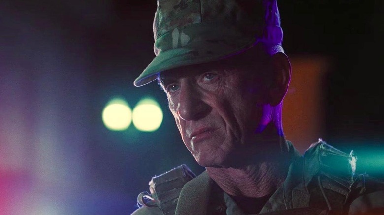 Sean Penn as Col. Steven J. Lockjaw in his cop uniform on the street in One Battle After Another