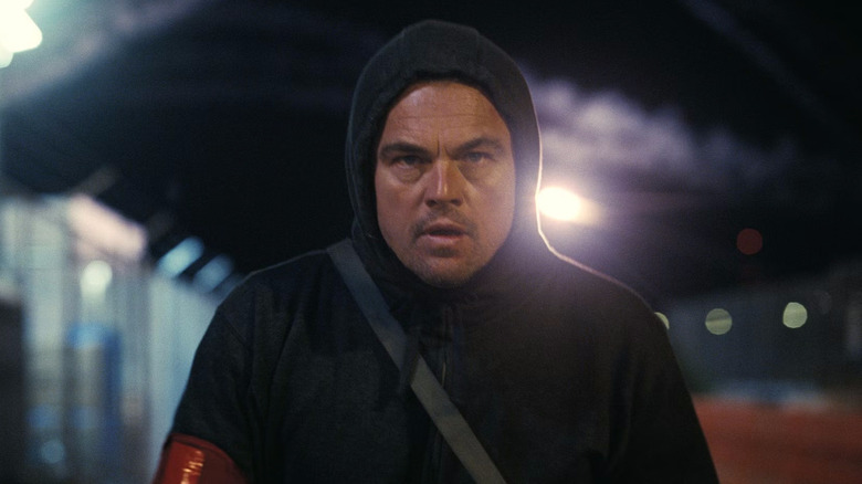 Leonardo DiCaprio as Bob walking away with his hoodie on in One Battle After Another