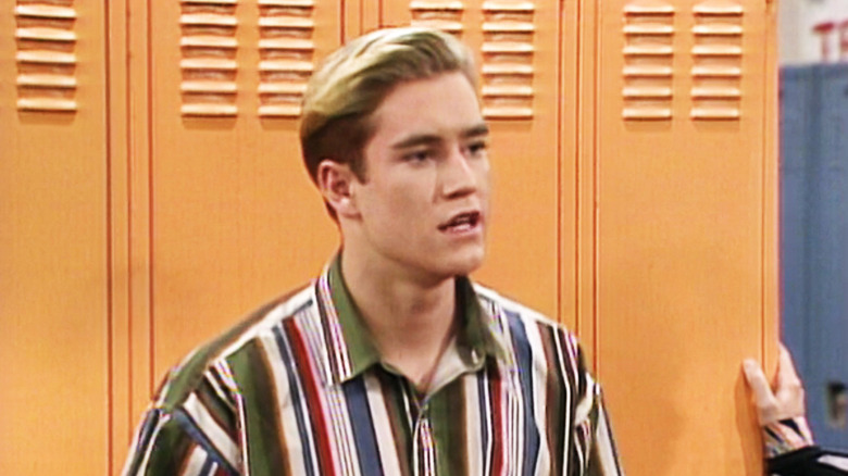 Mark-Paul Gosselaar's Zack Morris stands in front of lockers in Saved by the Bell