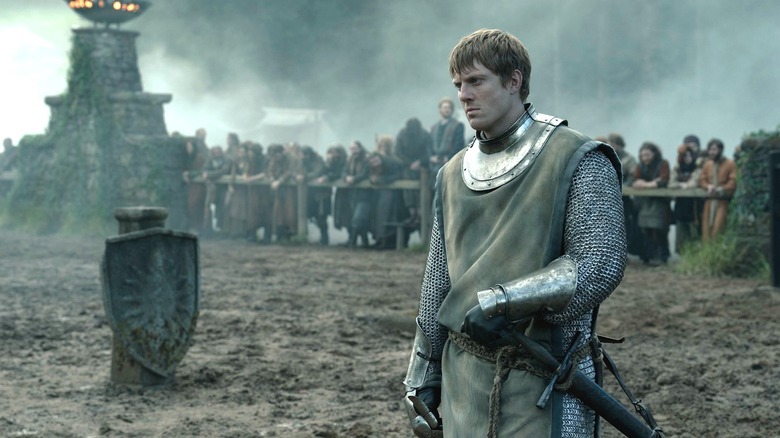 Peter Claffey as Ser Duncan the Tall dressed in armor and standing in a muddy field as onlookers watch in the background in A Knight of the Seven Kingdoms