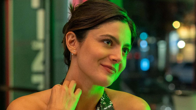 A smiling Allie is bathed in the green reflection of neon lights in Owen's pizza shop in One Night Only