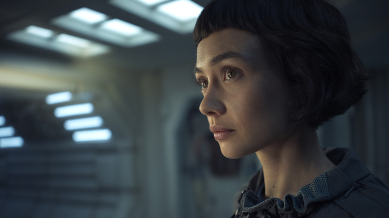 Sydney Chandler as Wendy standing in a brightly-lit corridor in Alien: Earth
