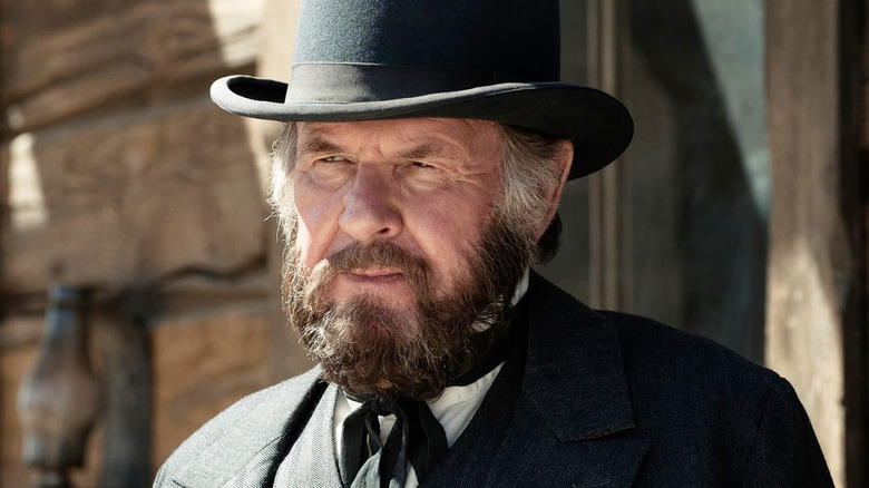 Tom Wilkinson as Latham Cole wearing a bowler hat and matching black suit in The Lone Ranger (2013)