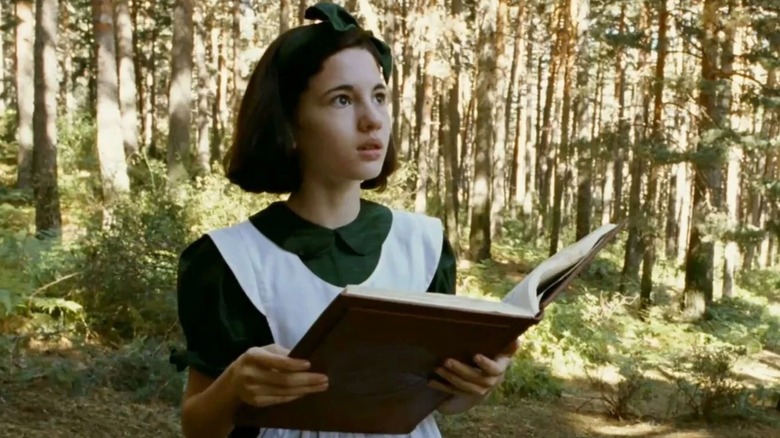 Pan's Labyrinth - Ofelia walking through woods holding open storybook
